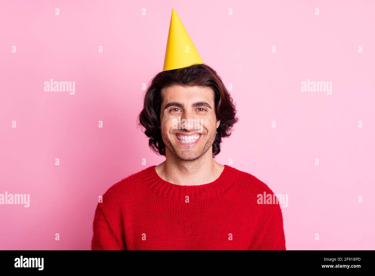 Photo portrait of smiling man wearing yellow party cone isolated on pastel pink colored background Stock Photo