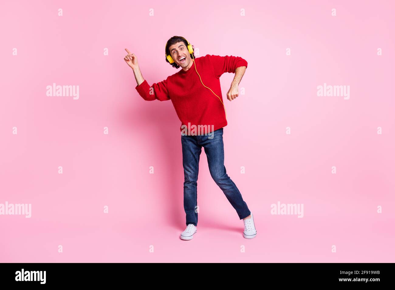 Full size photo of young carefree man have fun enjoy music earphones dance disco happy smile isolated over pink color background Stock Photo