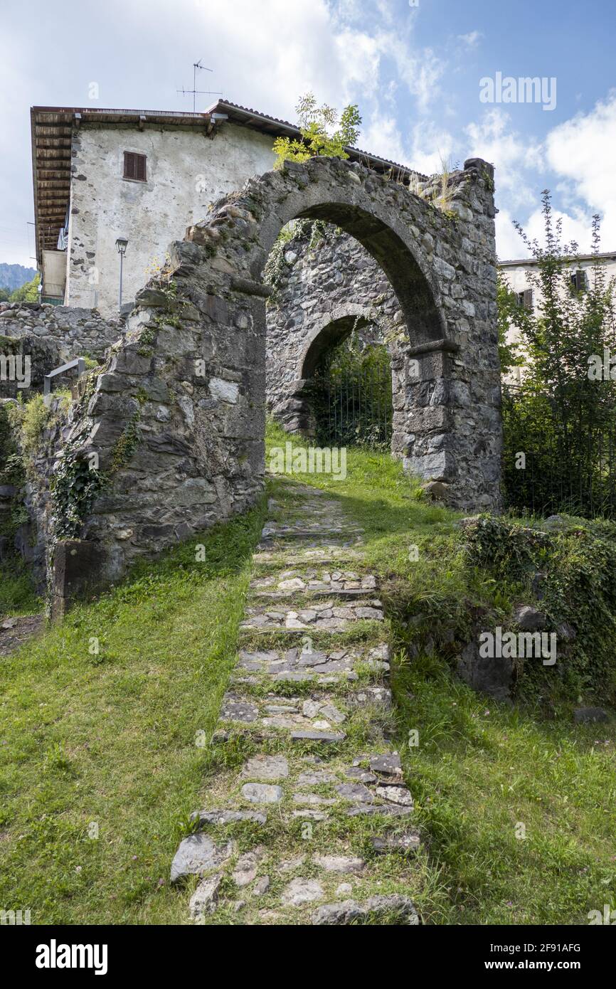 Stone walkway passing through a ruined arch in an ancient medieval village of Cornello dei Tasso Stock Photo