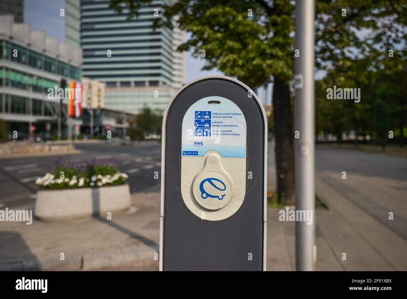 WARSAW. POLAND - AUGUST 2015: Charging station for an electric car in the city center against the background of a flower bed and a road. Stock Photo