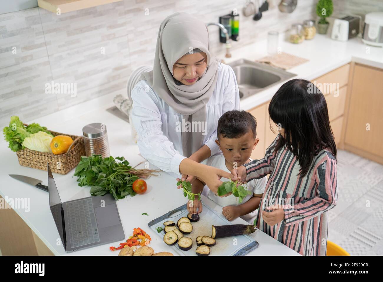lovely asian woman with daughter and son cooking dinner during ramadan Stock Photo