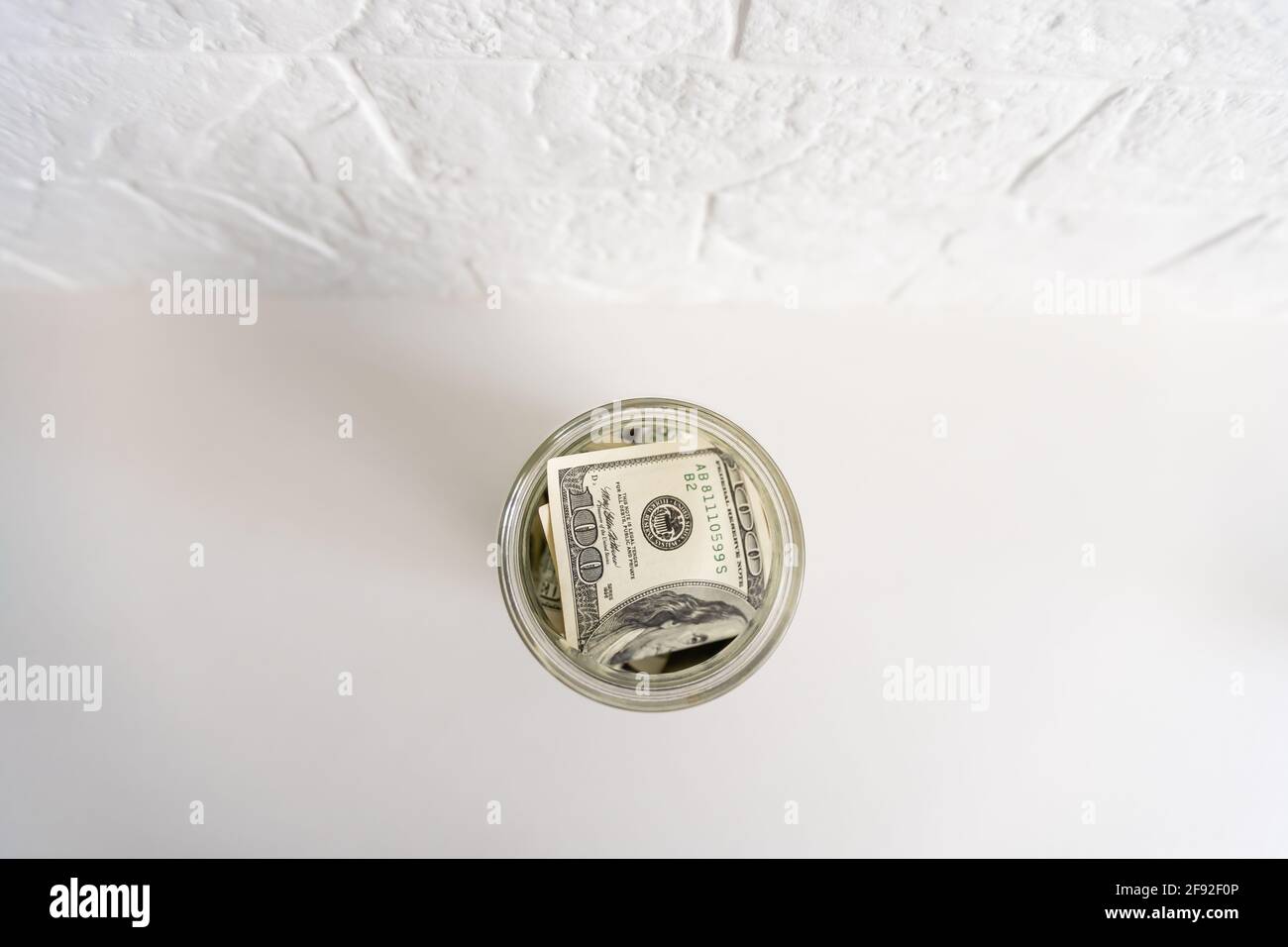 Many dollars bank notes in a glass jar isolated on white background ...