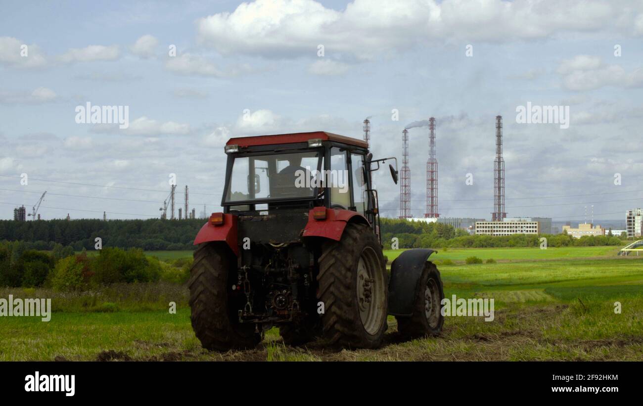 Photo of tractor and industrial factory in the field Stock Photo