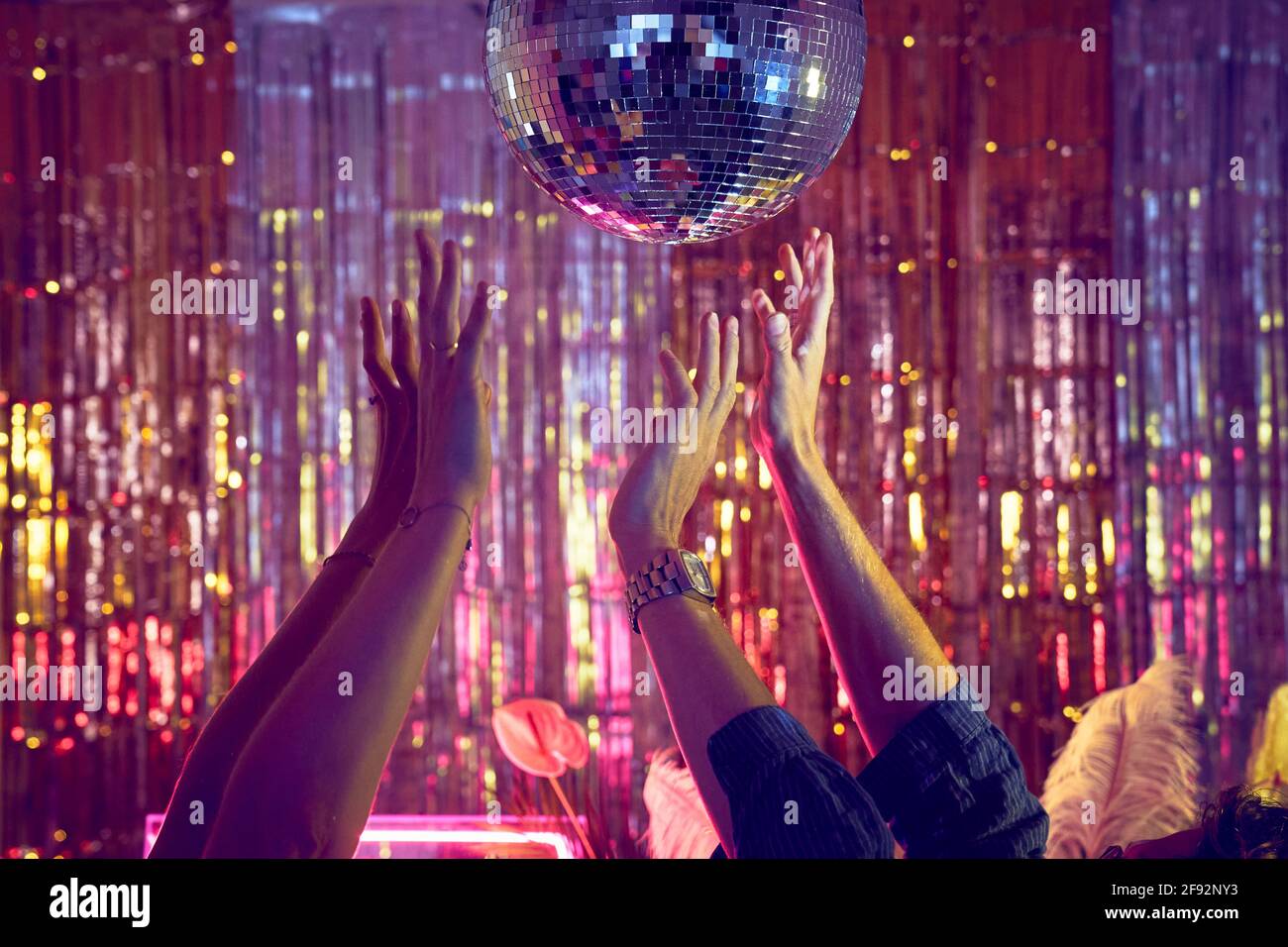 Disco dancing underneath the disco ball with hands in the air. Stock Photo