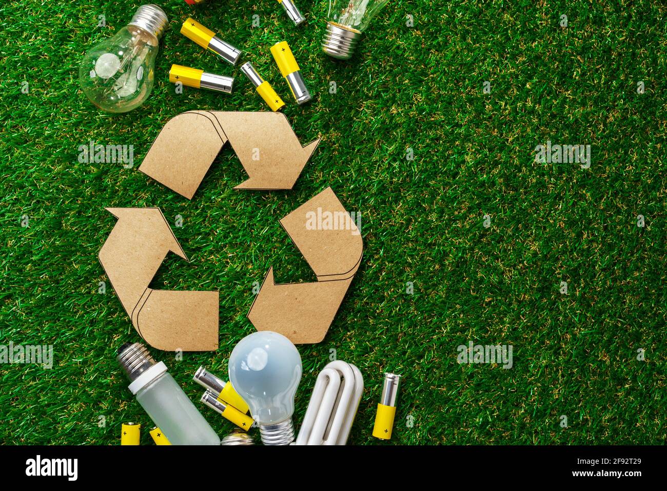Used metal lithium alkaline batteries and lightbulbs on grass