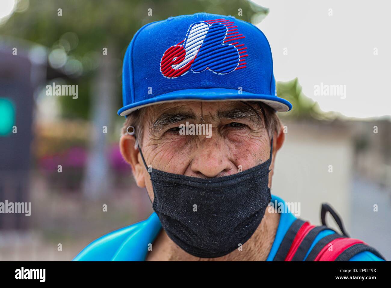 An older man wears a mask for Covid 19 and a blue cap from the defunct or  defunct Major League Baseball team, MLB, the Montreal Expos on April 15,  2021 in Hermosillo