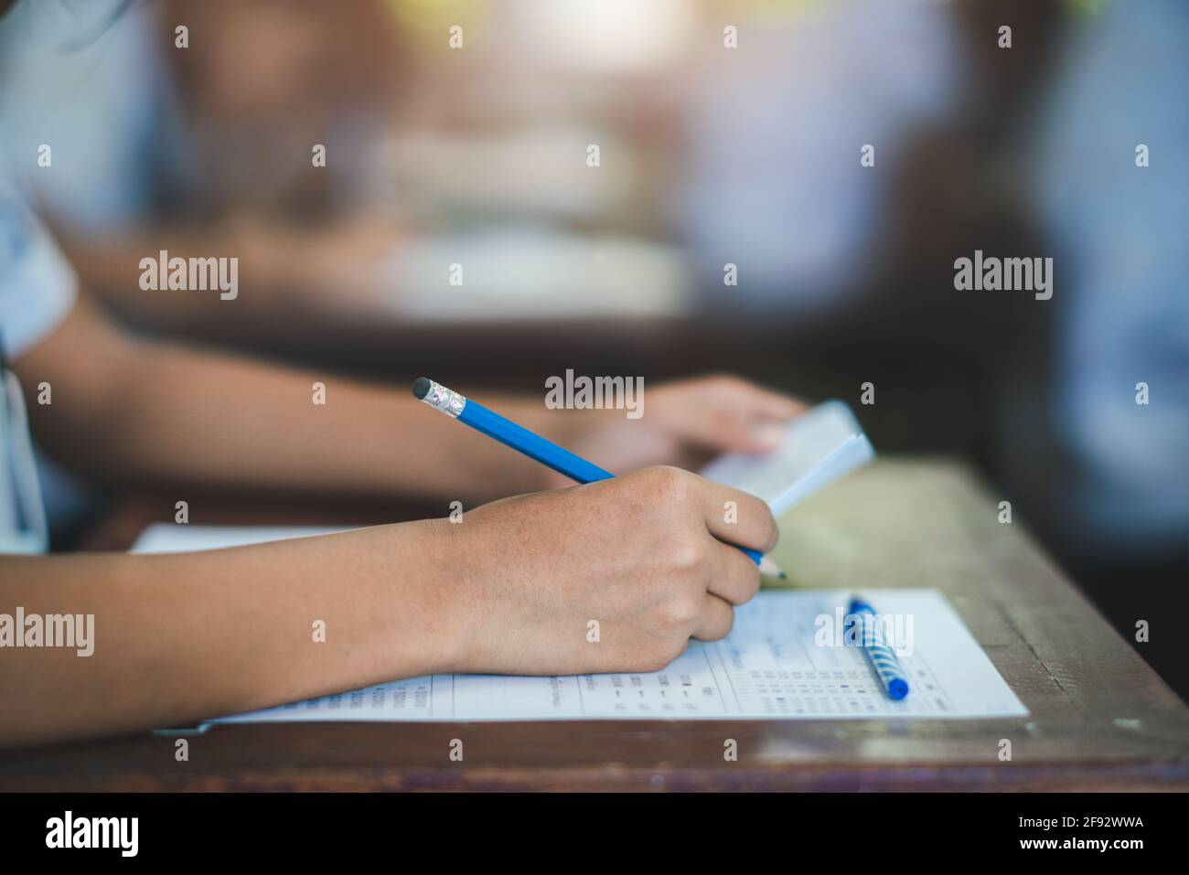 Students writing and reading exam answer sheets exercises in classroom of school with stress Stock Photo