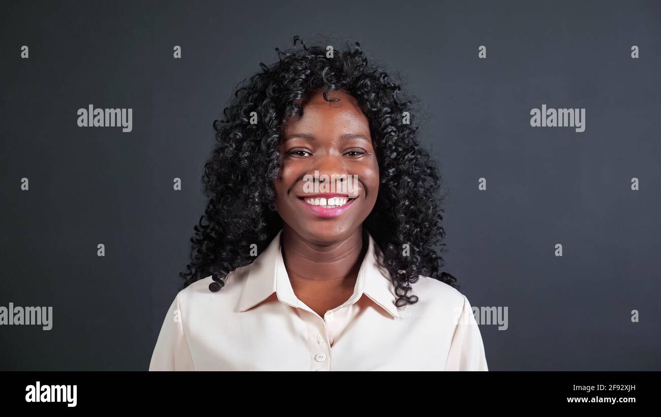 Attractive young African-American woman with curly hair smiles and ...