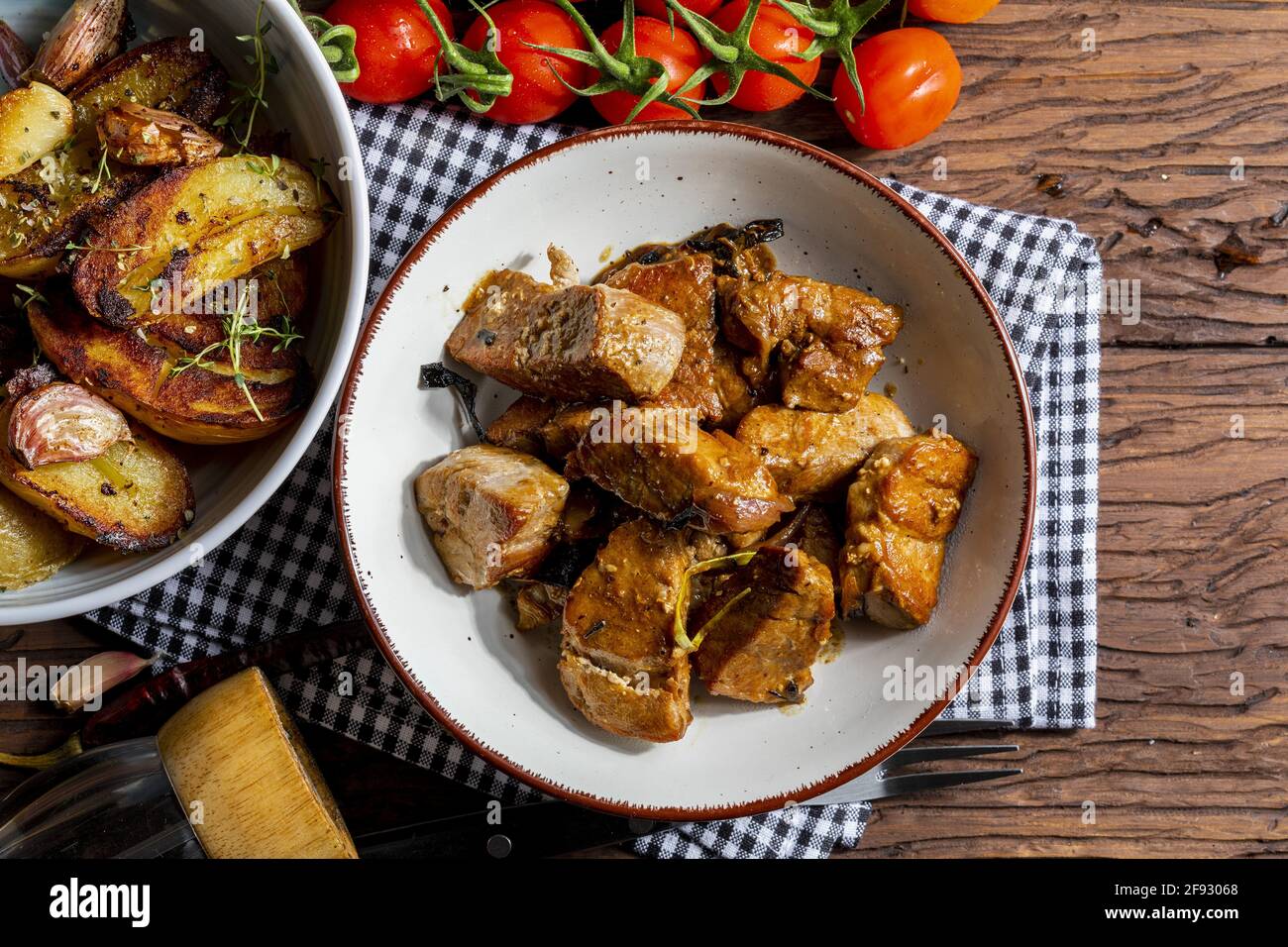 Appetizing stew of pork tenderloin meat cooked in the wok, cut into cubes. With roasted and golden potatoes, garlic, salt, oregano and fresh tomatoes. Stock Photo