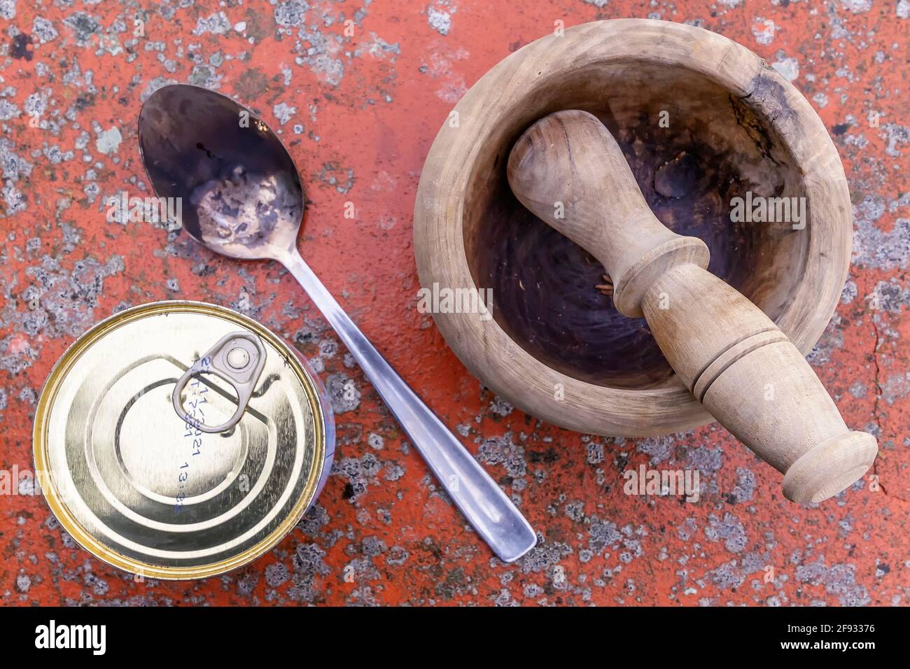 Top view of a can of packaged food, a wooden mortar and a metal spoon on a spotted background Stock Photo