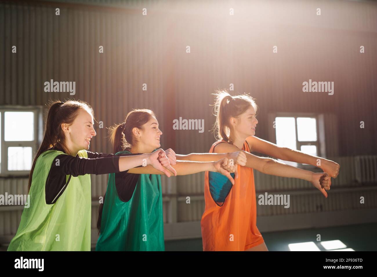 People, sporty friendship women, football fans, indoor gym, cheer up support favorite team with soccer ball showing thumbs down, sunny daylight. Stock Photo