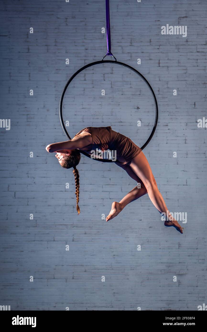Female circus aerialist acrobat training on the hoop. Strong woman