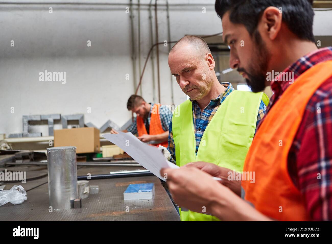 Two workers or skilled workers discuss an order in the locksmith workshop Stock Photo