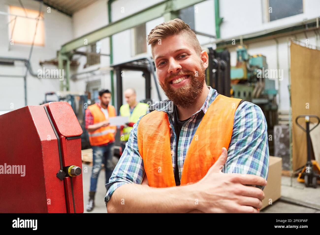 Smiling young man as a warehouse worker or metal worker trainee in a warehouse Stock Photo