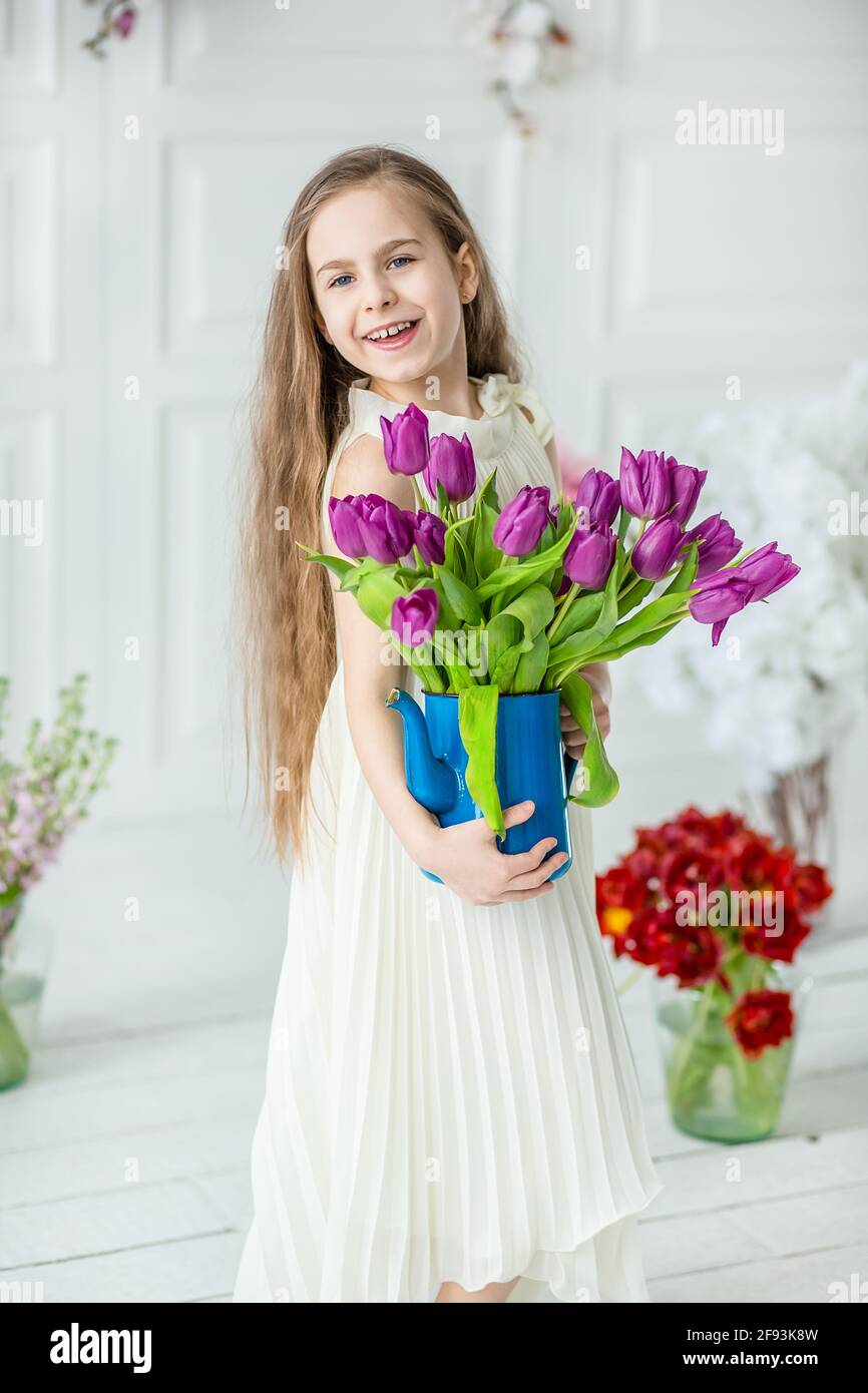 Little beautiful little girl with blonde long hair, in white dress