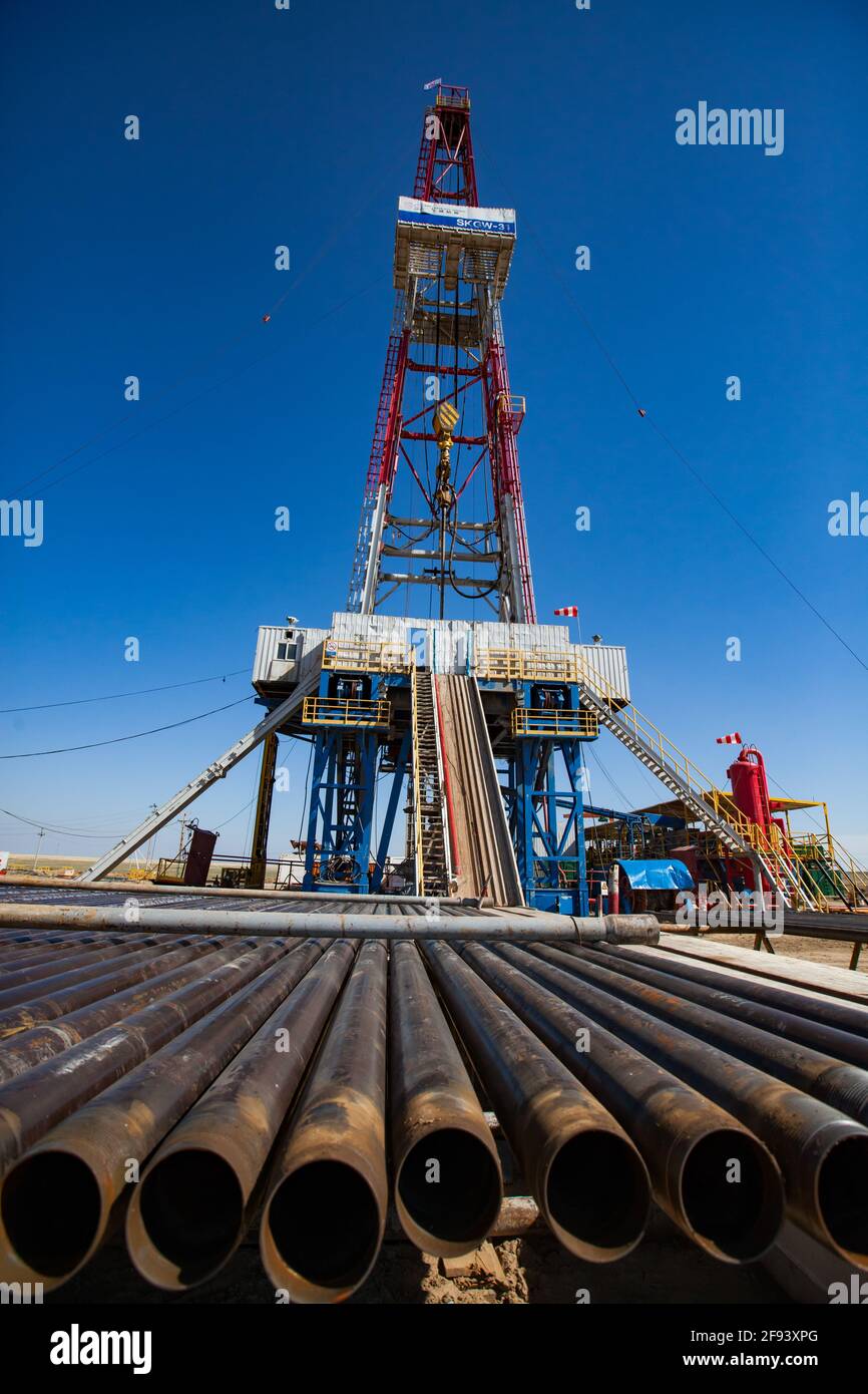 Aktobe region, Kazakhstan. Extraction of oil from deposit in desert with rig. Drilling pipes, derrick and equipment on clear blue sky background Stock Photo