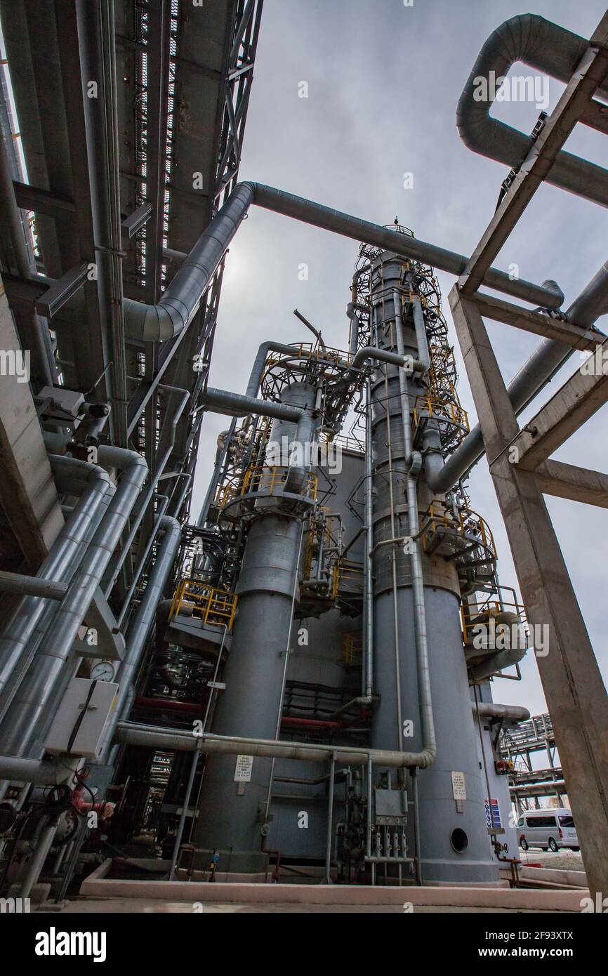 Distillation tower (column) on blue sky with sun background. Oil