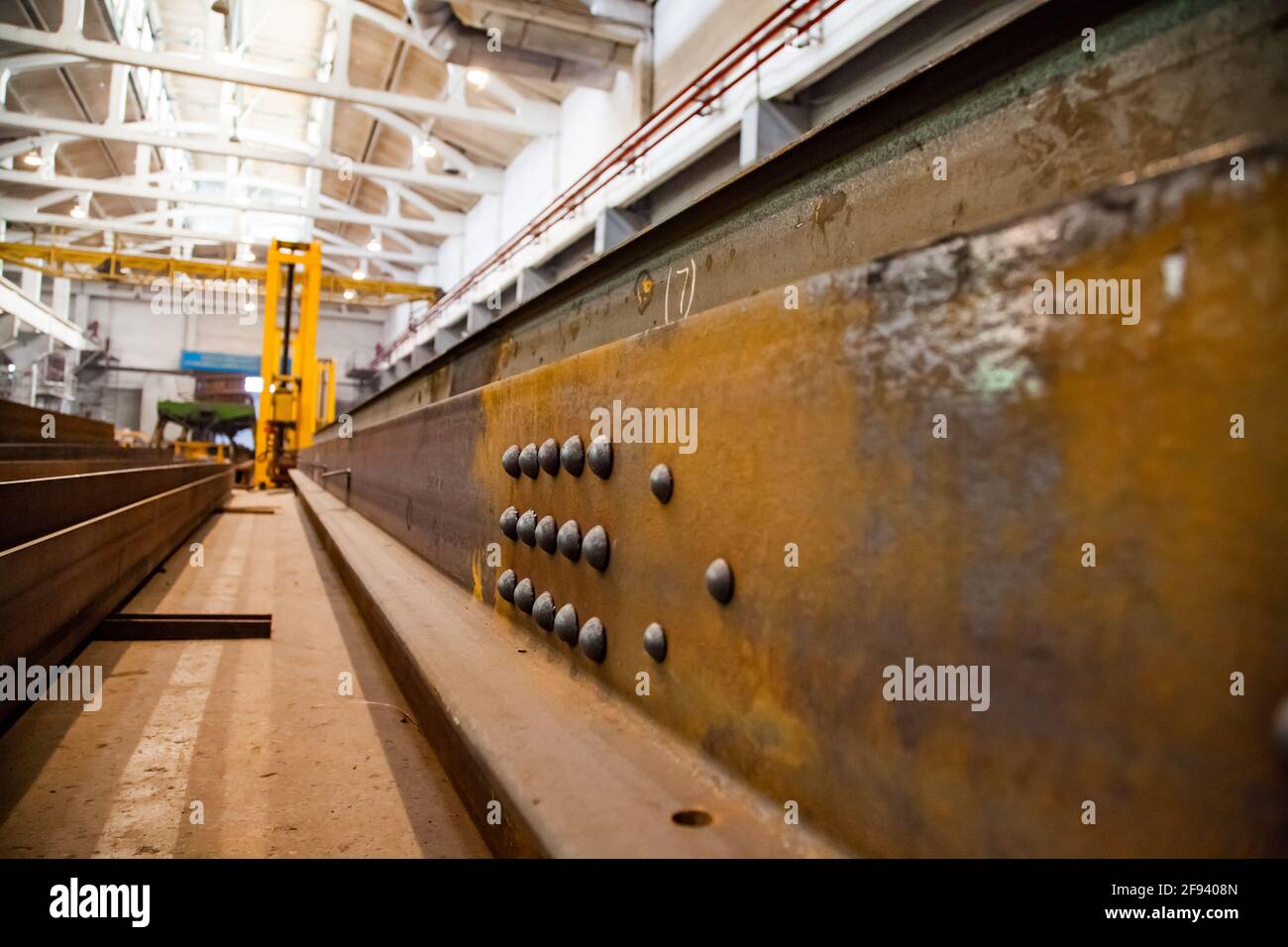 Train car-building plant. View on large steel detail with rivets (clinches). Low depth-of-field. Focus on rivets. Stock Photo