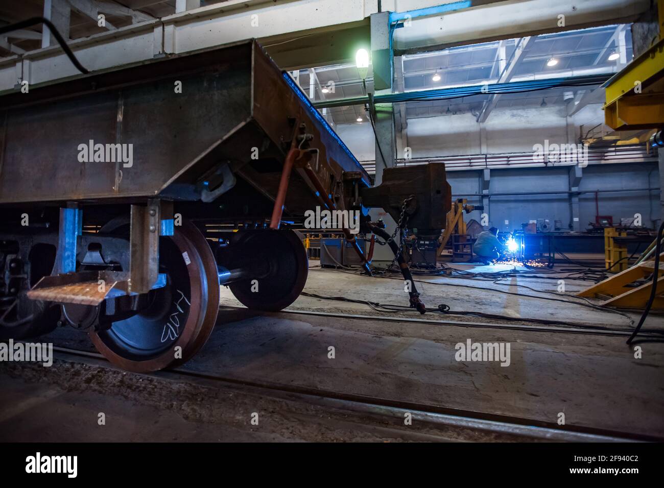 Train car-building plant. Welding metal parts on background. Train car on foreground. Focus on worker. Stock Photo