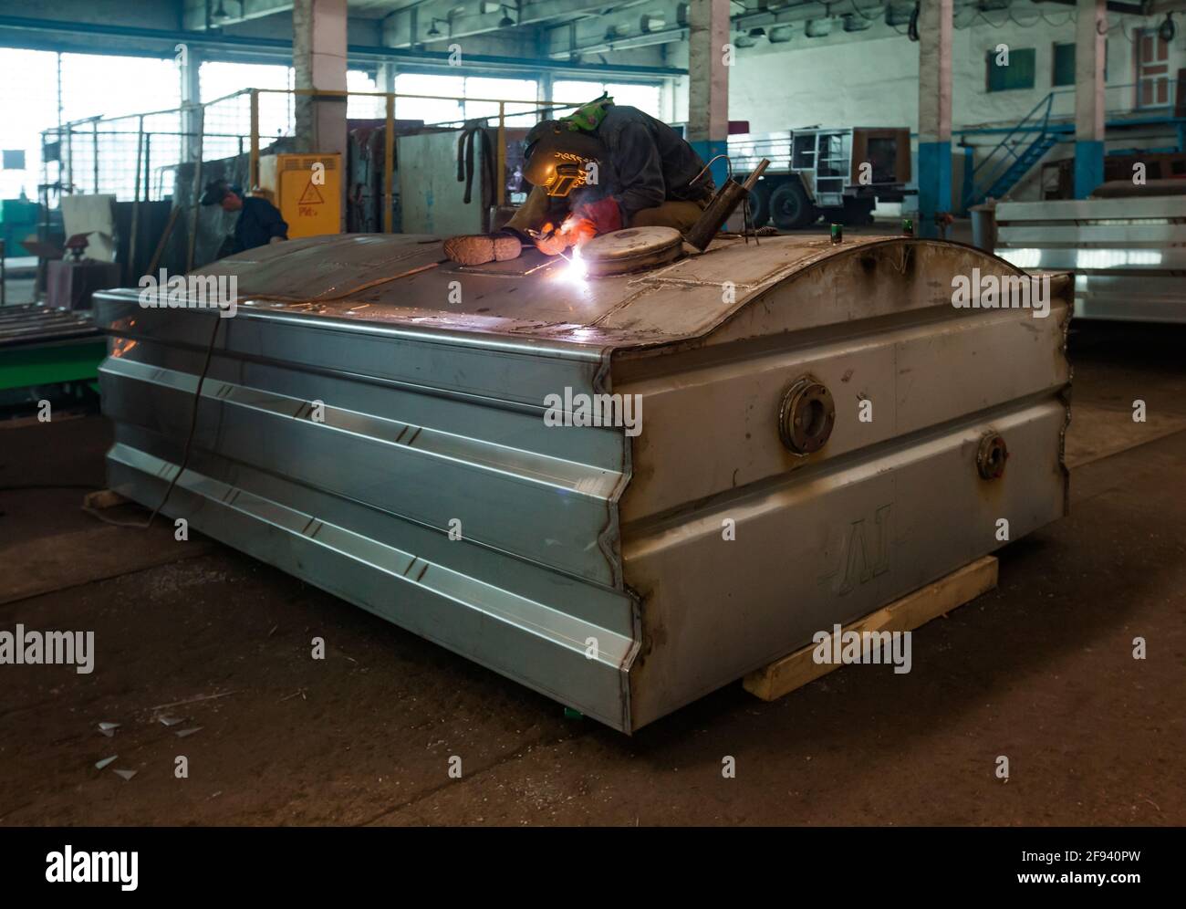 Welder worker welding metal truck cistern. Car-building factory workshop. Stock Photo