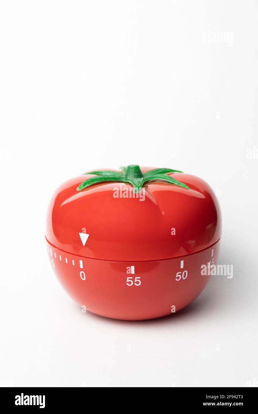 Pomodoro timer - mechanical tomato shaped kitchen timer for cooking or studying on the grey background. Place for your text. Stock Photo