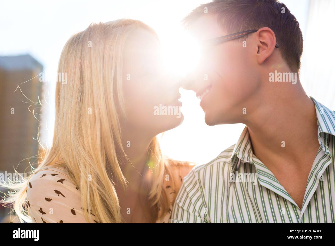 Couple sitting in the sun and kisses because happiness is tangible Stock Photo