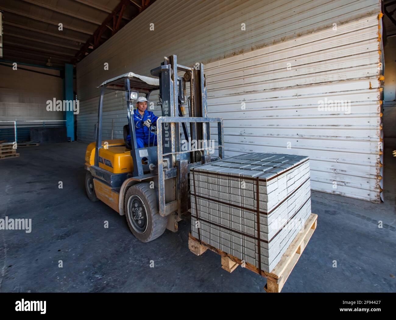 Loading paving tile stack to warehouse. Production plant. Asian worker