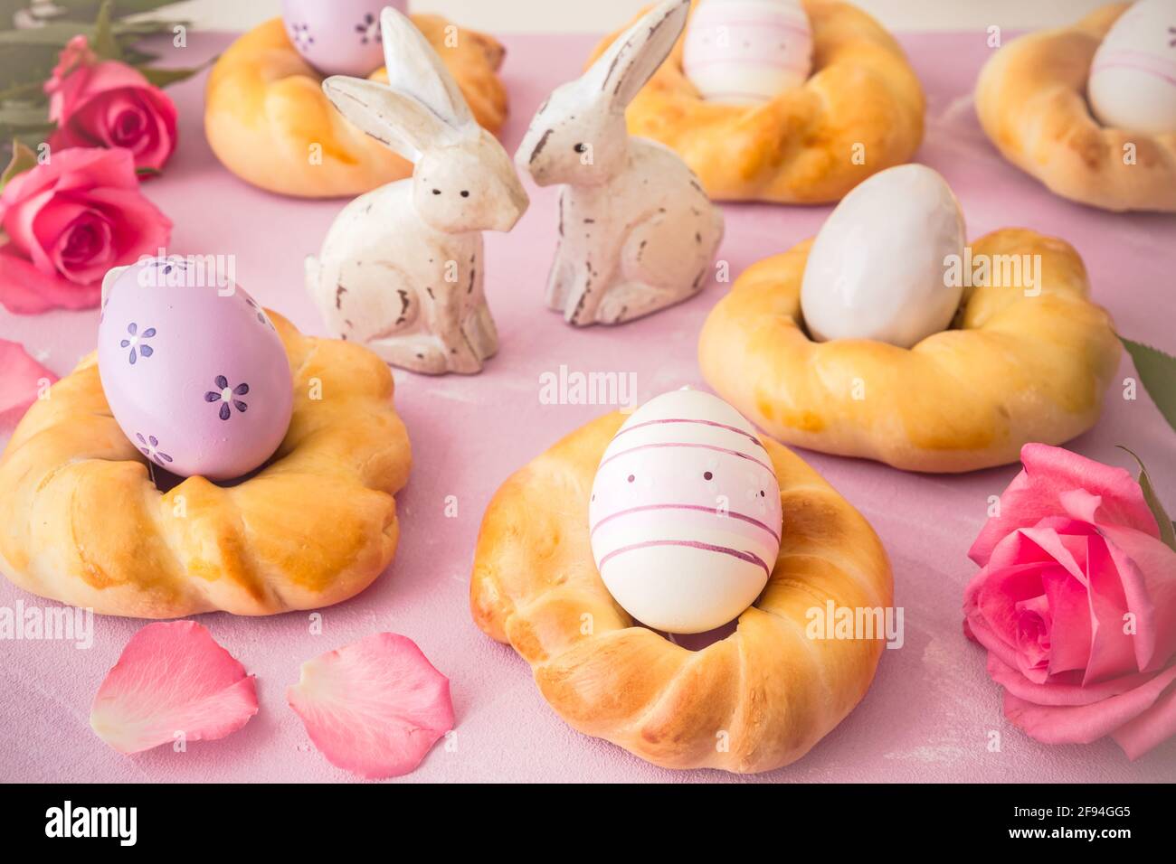 Homemade easter buns with colorful easter eggs on pinkish background Stock Photo