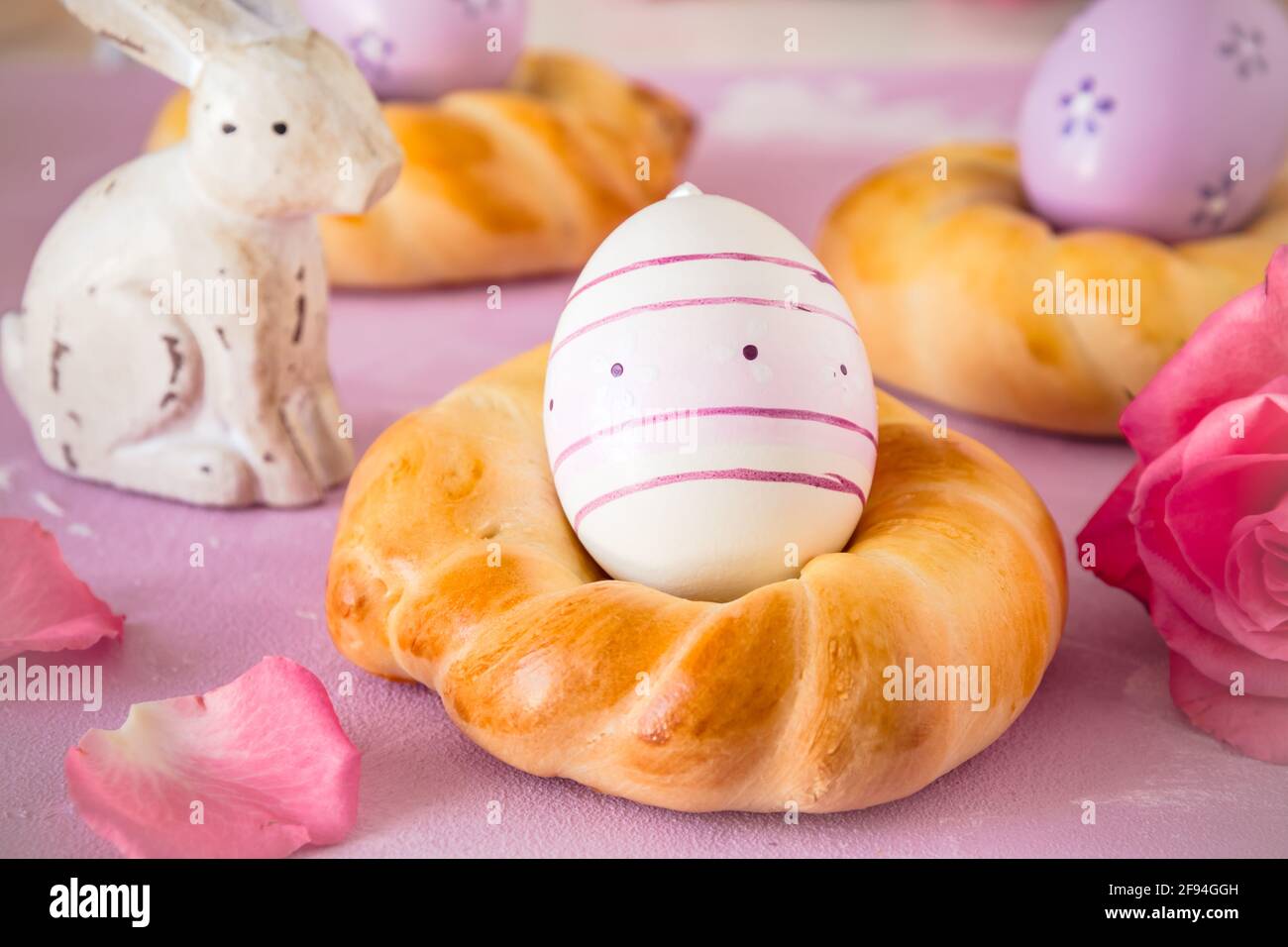 Homemade easter buns with colorful easter eggs on pinkish background Stock Photo