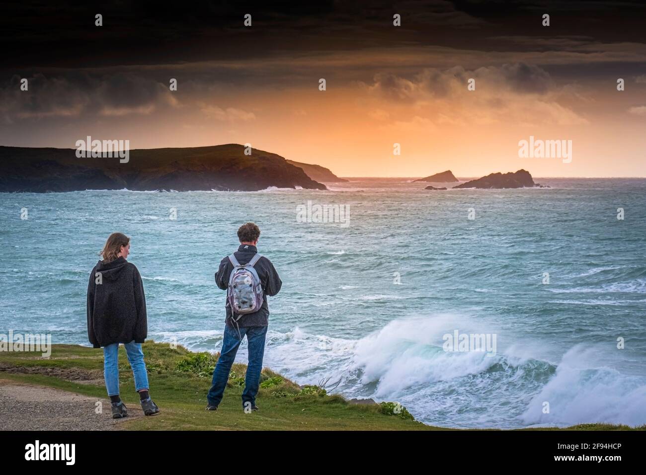 Two people standing on the coast path overlooking Fistral Bay in Newquay in Cornwall. Stock Photo