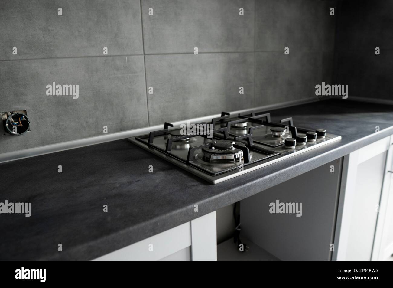 Stainless grey metal kitchen gas stove installed on a the kitchen with a  dark grey table top Stock Photo - Alamy