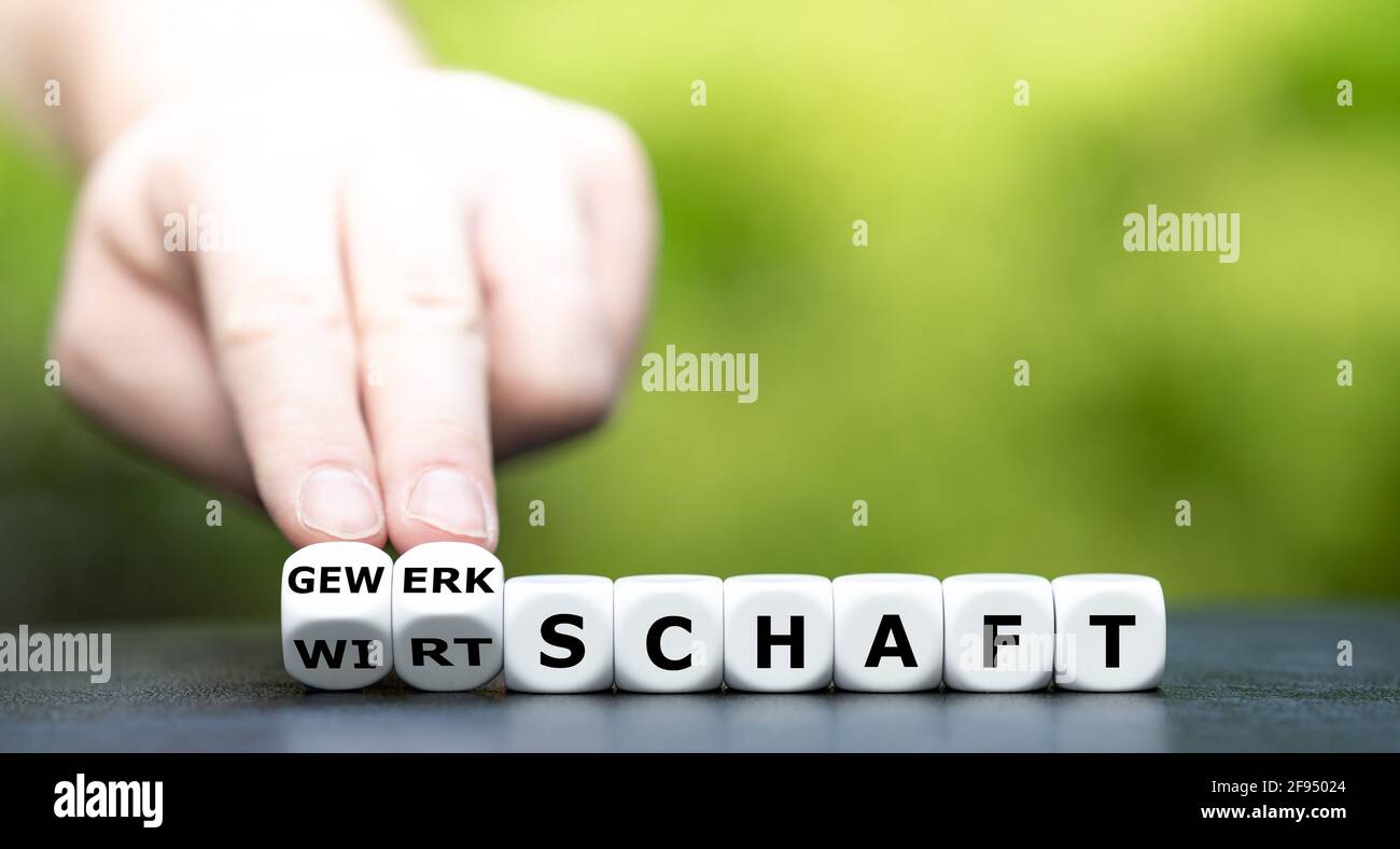Hand turns dice and changes the German expression 'Wirtschaft' (economy) to 'Gewerkschaft' (labor union). Stock Photo
