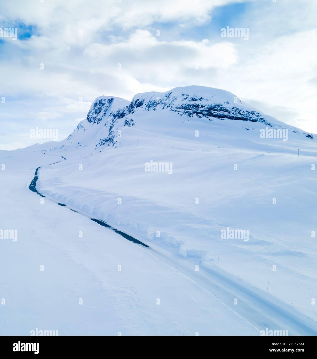 Lonely frozen road winding through a snow covered mountain landscape. Stock Photo