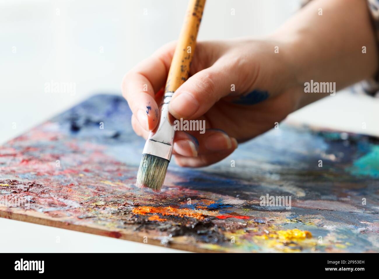 Artist paints a picture of oil paint brush in hand with palette close ...