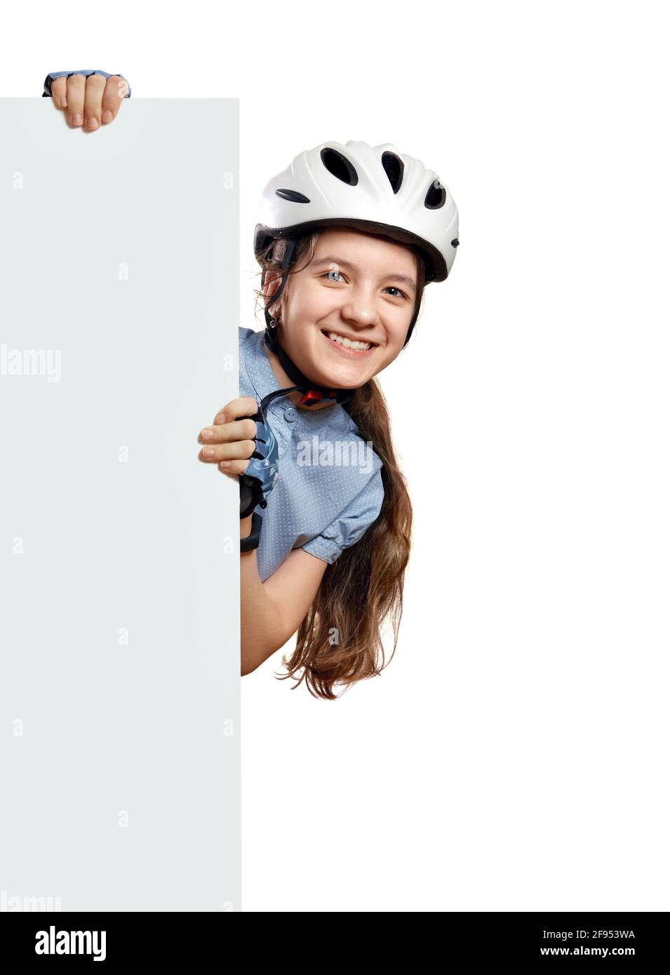 Young girl in white  bicycle helmet holds vertical white blank,Isolated on white Stock Photo