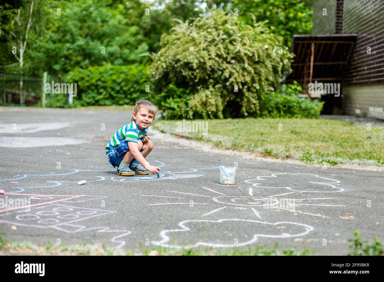 Cute boy and girl drawing with chalk on the sidewalk in the park ...