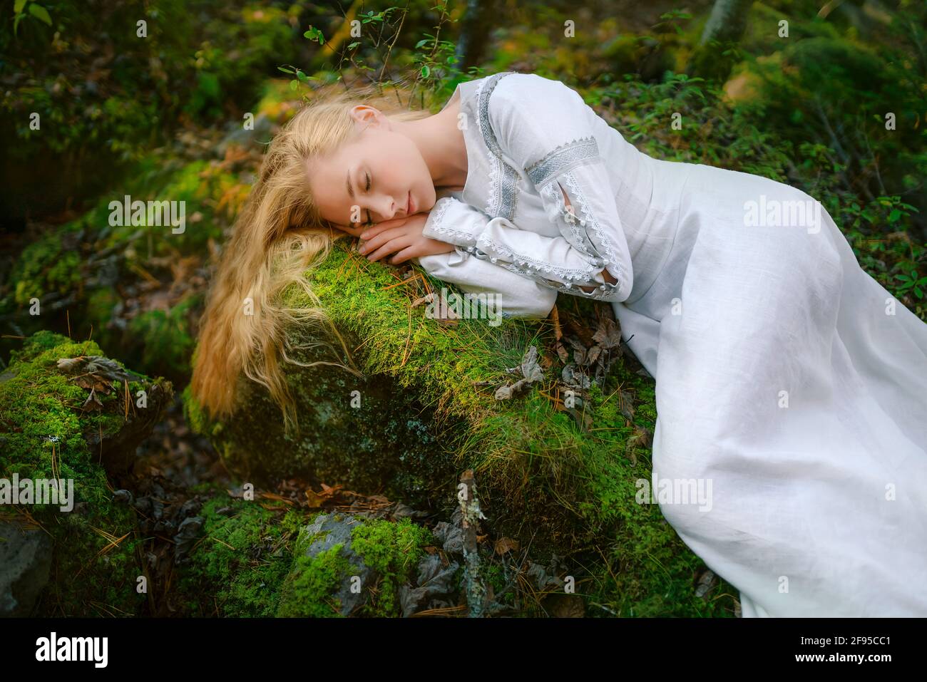 Beautiful young woman in a white dress in the middle of a forest Stock Photo