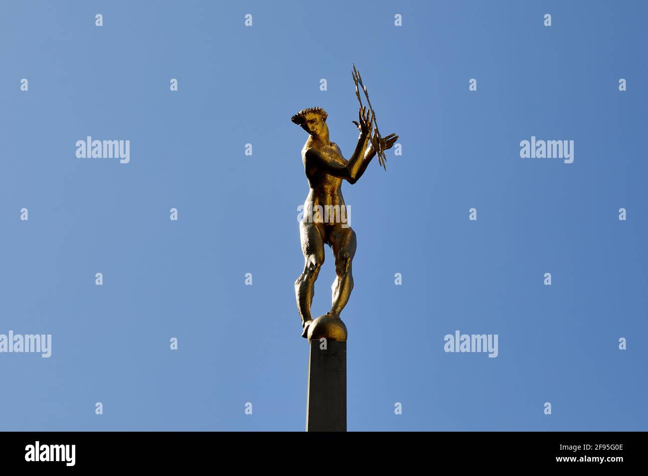 London, UK - 4 Apr 2021: The gilded bronze figure of Helios, the all-seeing Sun God of Greek mythology, which adorns the central courtyard of Television Centre in White City. The statue, designed by sculptor T B Huxley-Jones, was commissioned for the former BBC broadcasting hub, opened in 1960. Representing the radiation of television light around the world, the statue sits at the centre of a fountain and two reclining figures representing sound and vision, the two components of television. Stock Photo