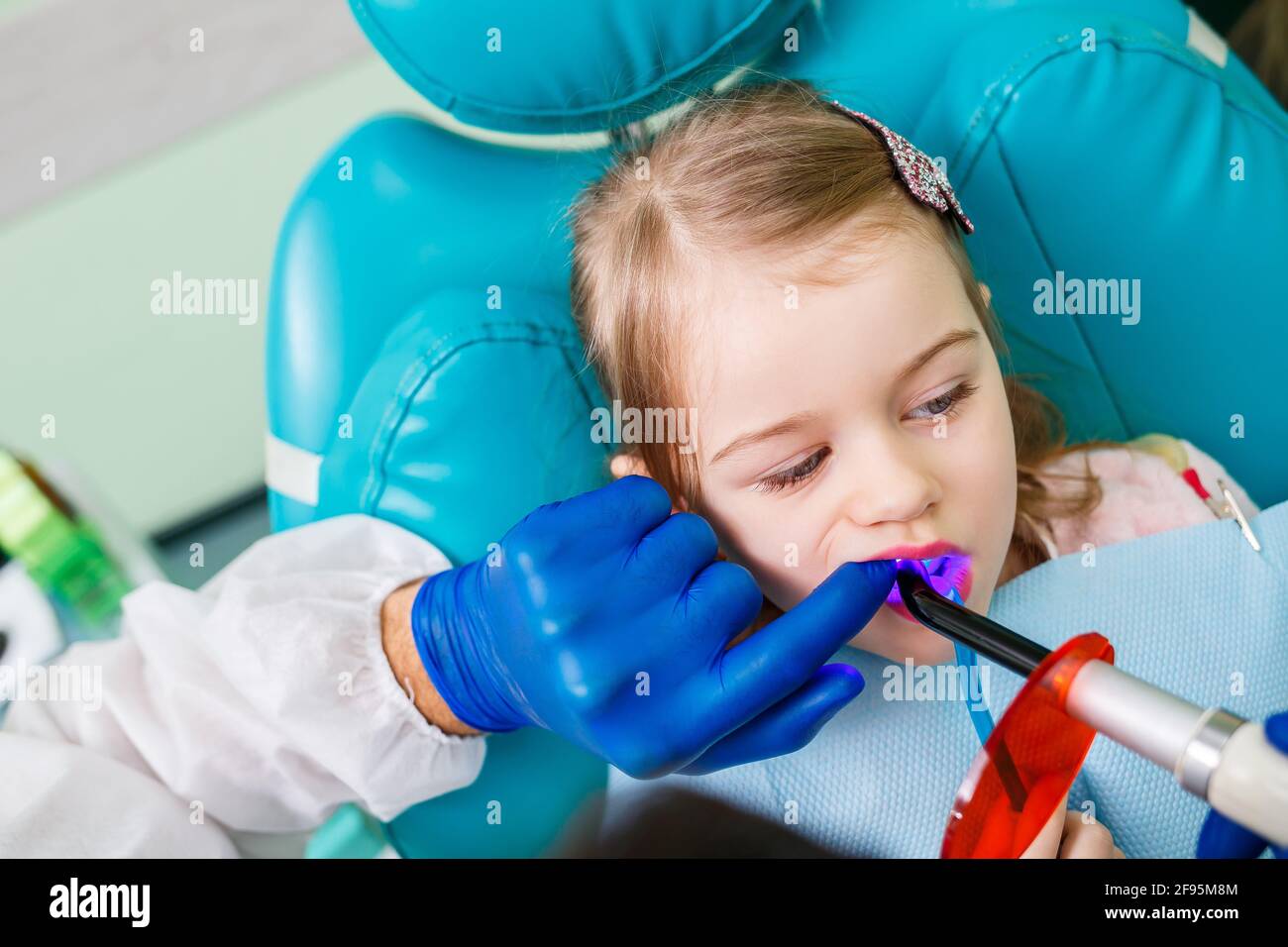 A professional doctor, a children's dentist, treats a little girl's