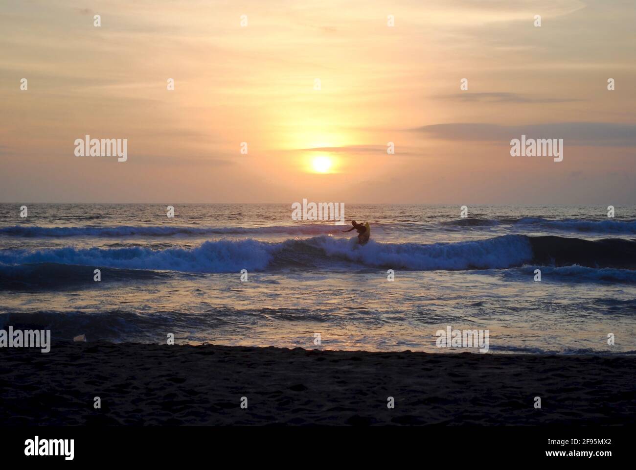Surfer at sunset. Legian Beach, Pantai Legian, Bali, Indonesia. Bali is a popular surf spot with many surf schools. Near Kuta and Seminyak. Stock Photo