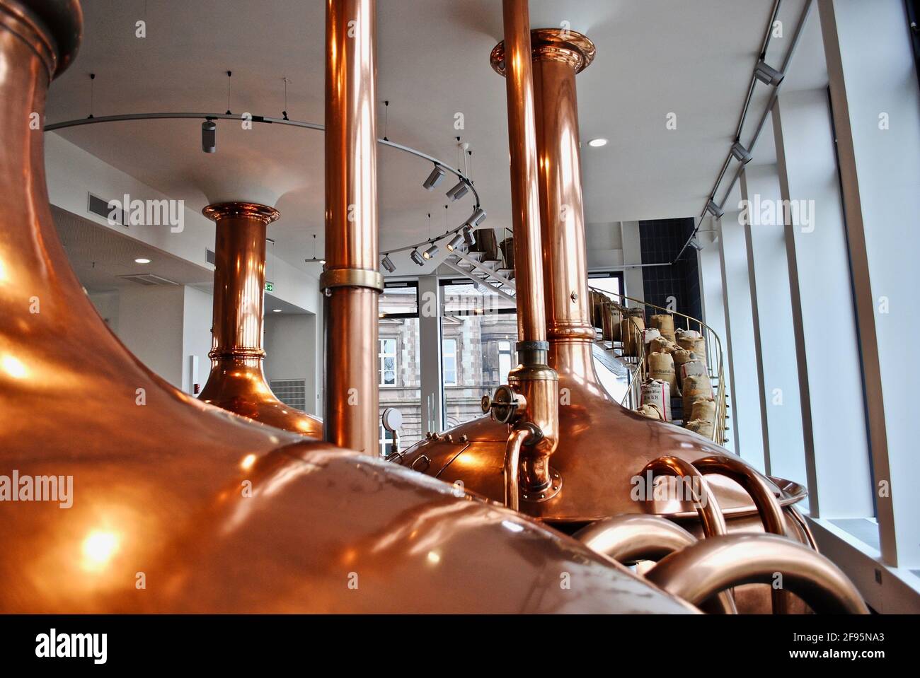 Bitburg, Germany: Bitburger Brewery (Bitburger Brauerei) is a large German brewery. Copper brew kettle and spiral stairs with burlap bags of malt. Stock Photo