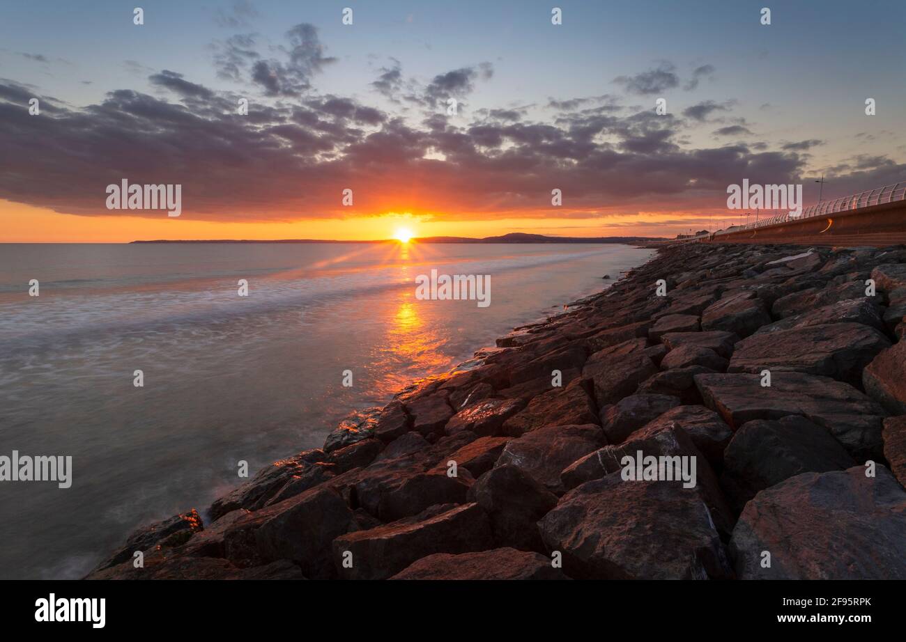 Sunset at Aberavon beach on an incoming tide with Swansea on the horizon, South Wales, UK Stock Photo