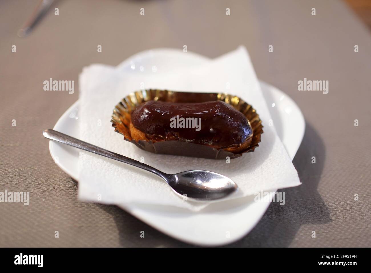 Chocolate eclair on the white plate in a cafe Stock Photo