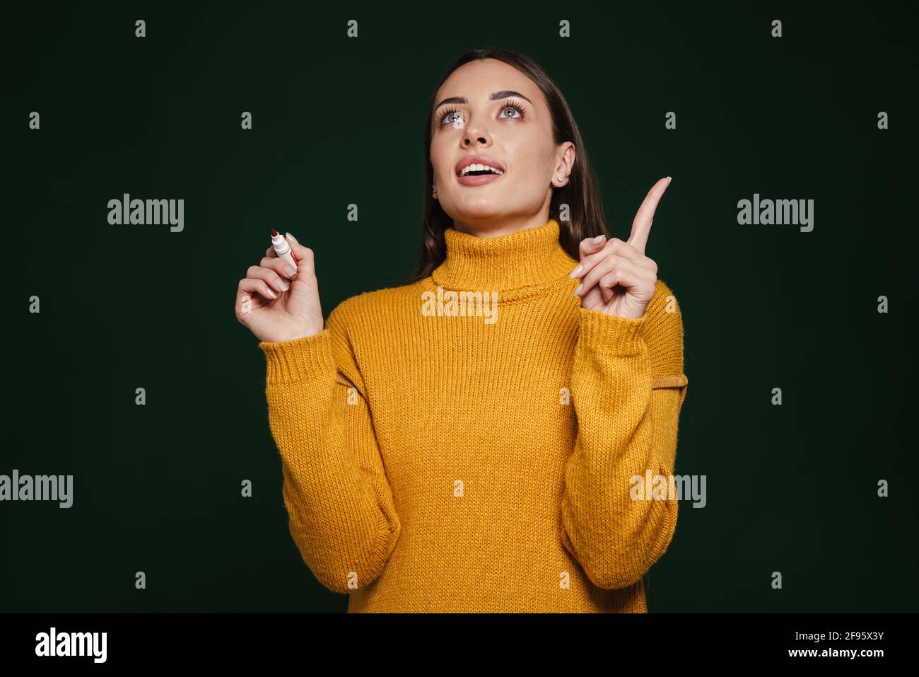 Beautiful thinking girl pointing finger upward while posing with marker ...