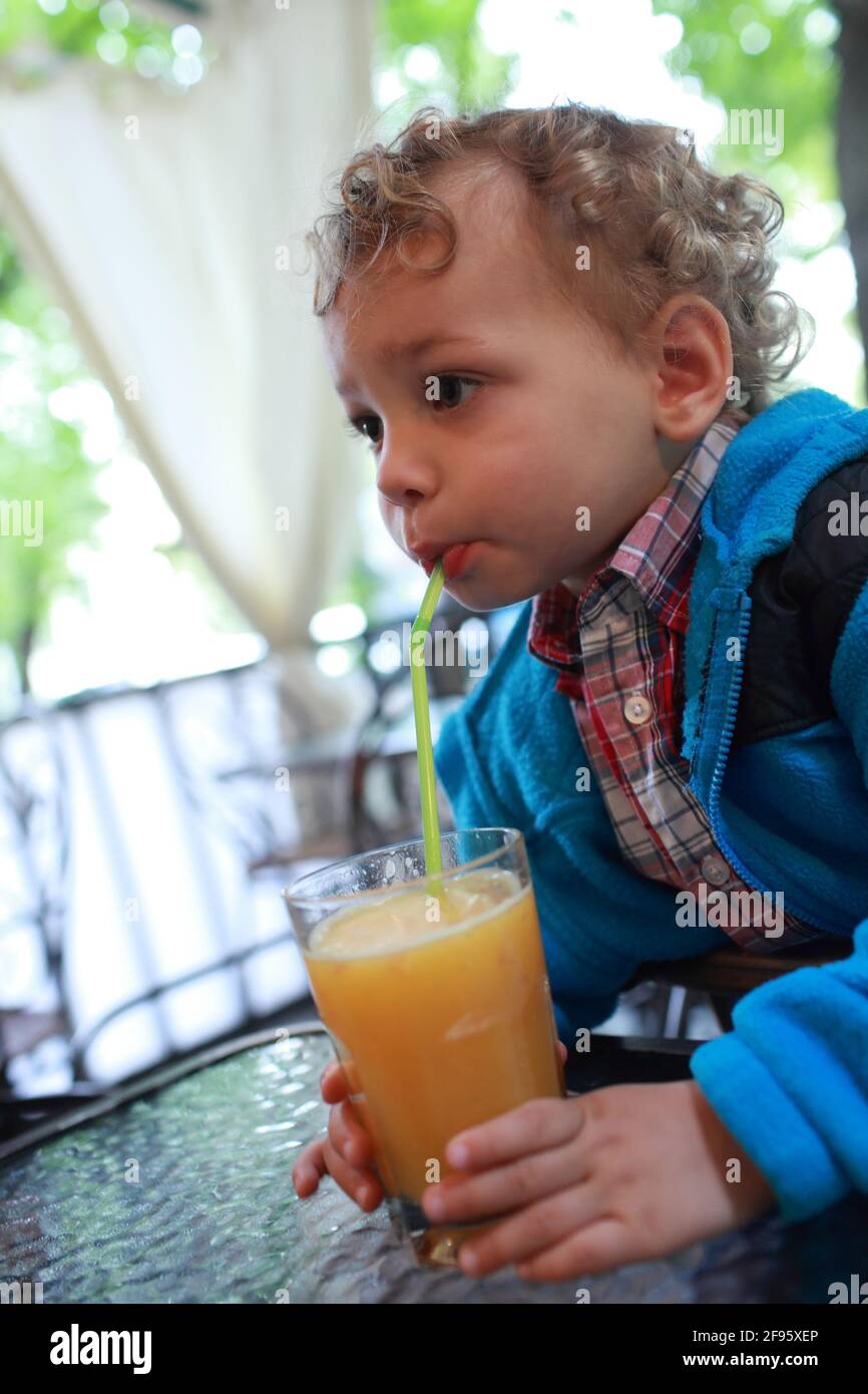 The toddler drinks juice in a cafe Stock Photo Alamy