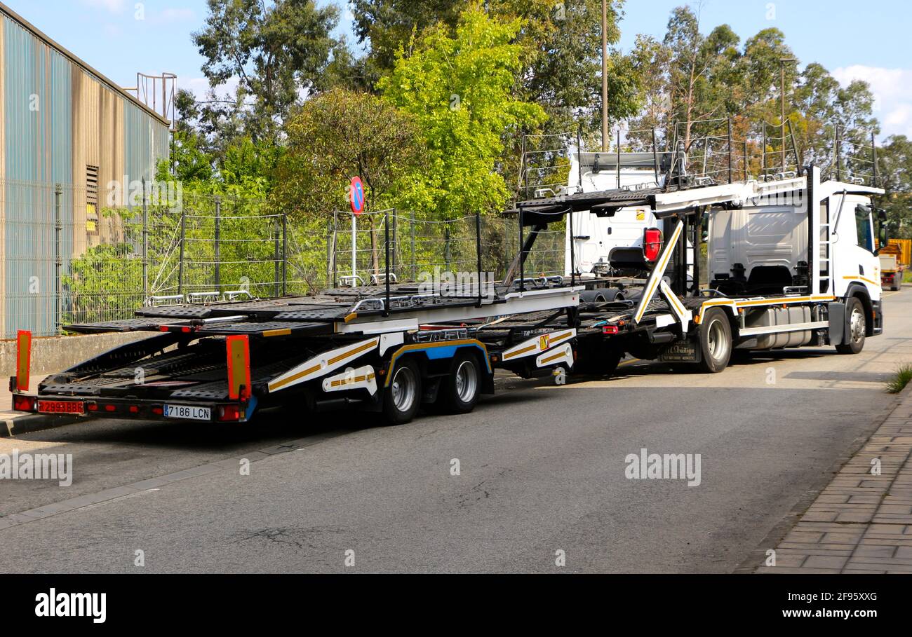 Empty open car carrier trailer leaving from a side street in an industrial area of Santander Cantabria Spain Sunny spring morning Stock Photo