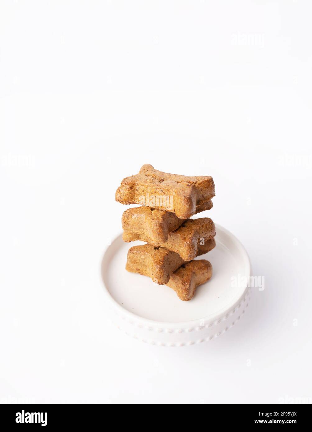 Stack of five bone shaped dog treats on mini cake pedestal on white