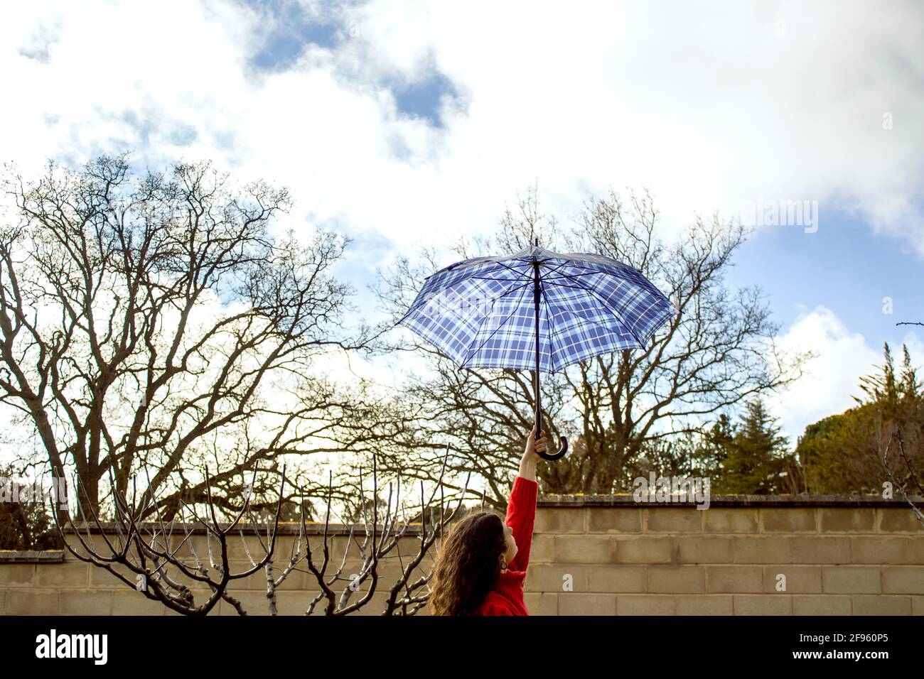 woman's arm holding an umbrella against cloudy sky Stock Photo