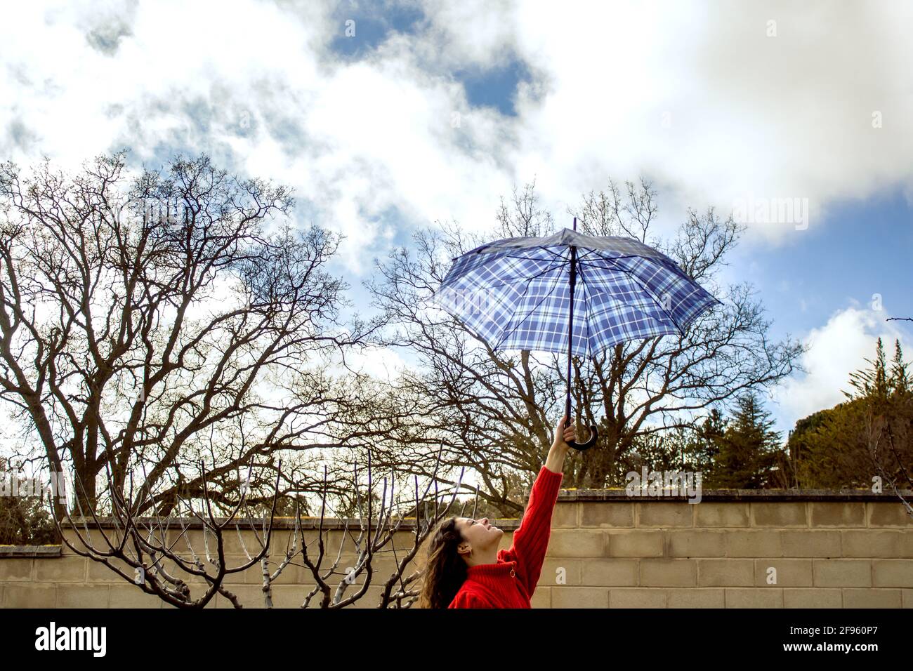 woman's arm holding an umbrella against cloudy sky Stock Photo