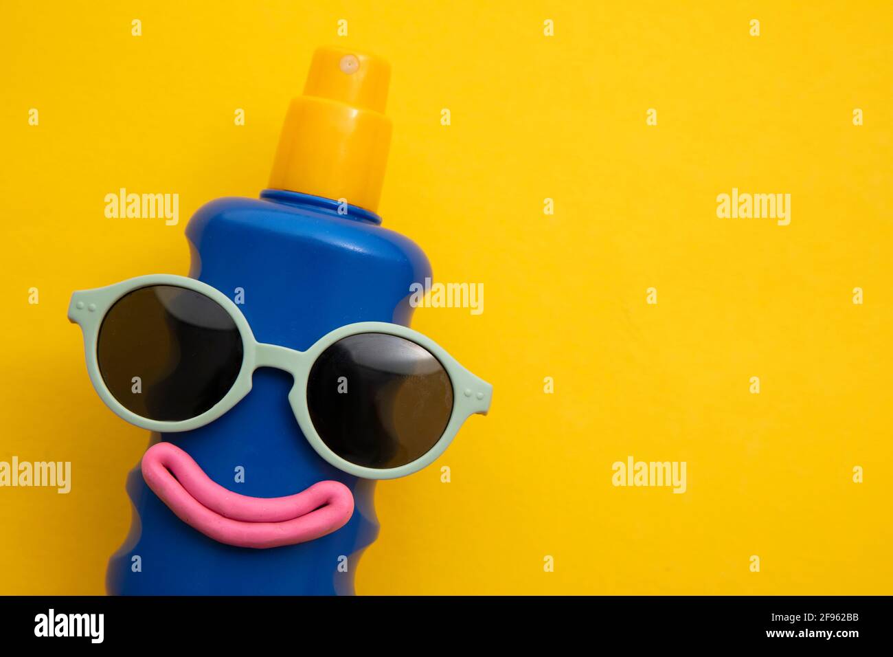 Happy sun block bottle wearing sunglasses and a smile on a yellow background Stock Photo